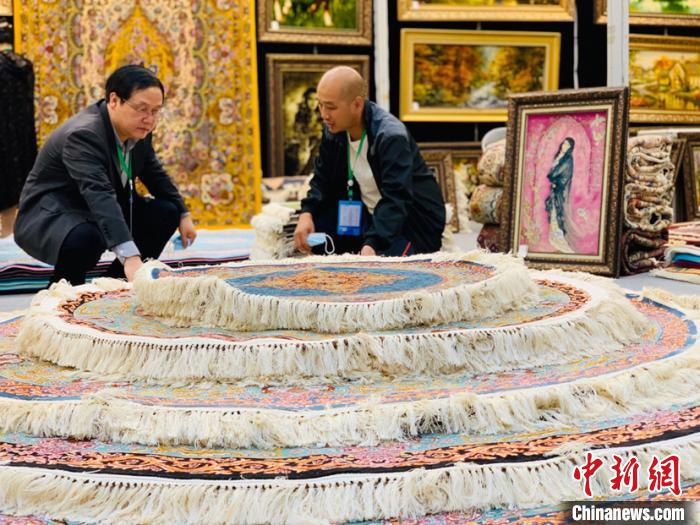 圖為參展商向咨詢的客商介紹地毯?！O睿 攝